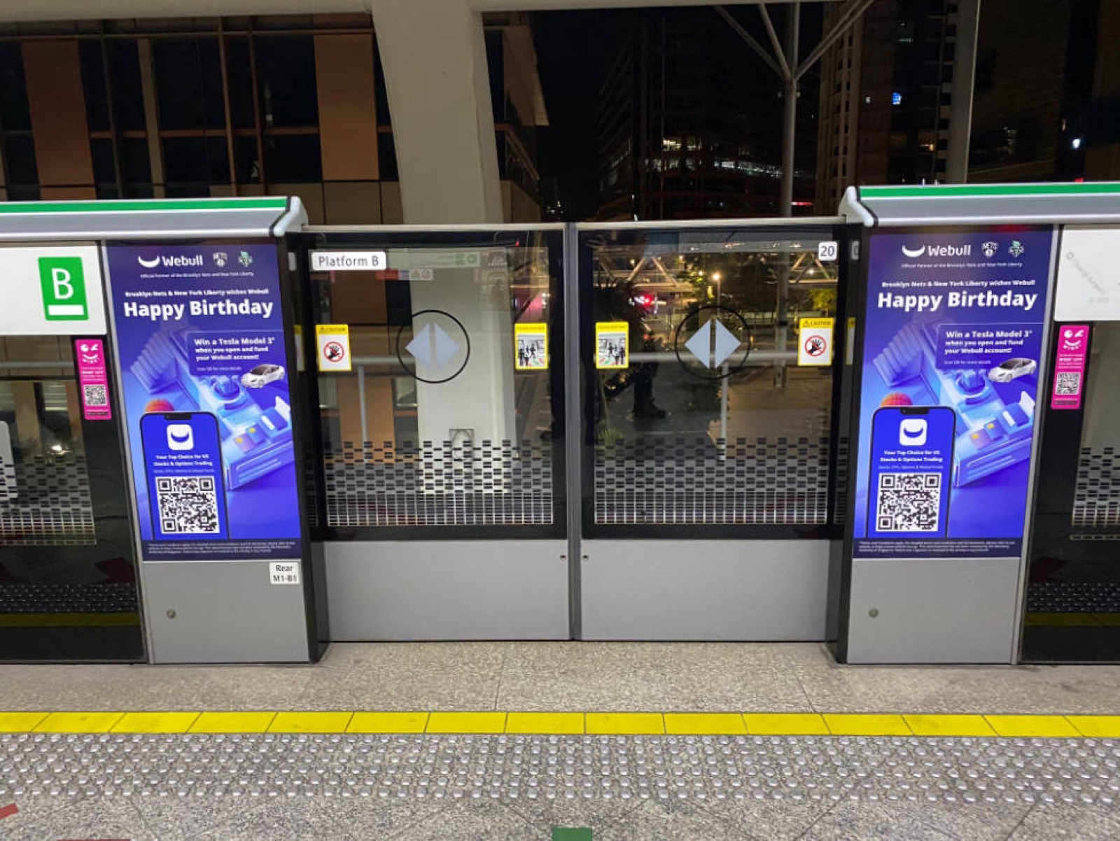Webull Happy Birthday campaign on platform screen doors at night