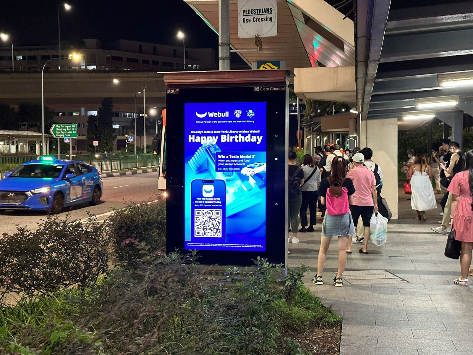 Webull digital bus shelter panel at Serangoon at night