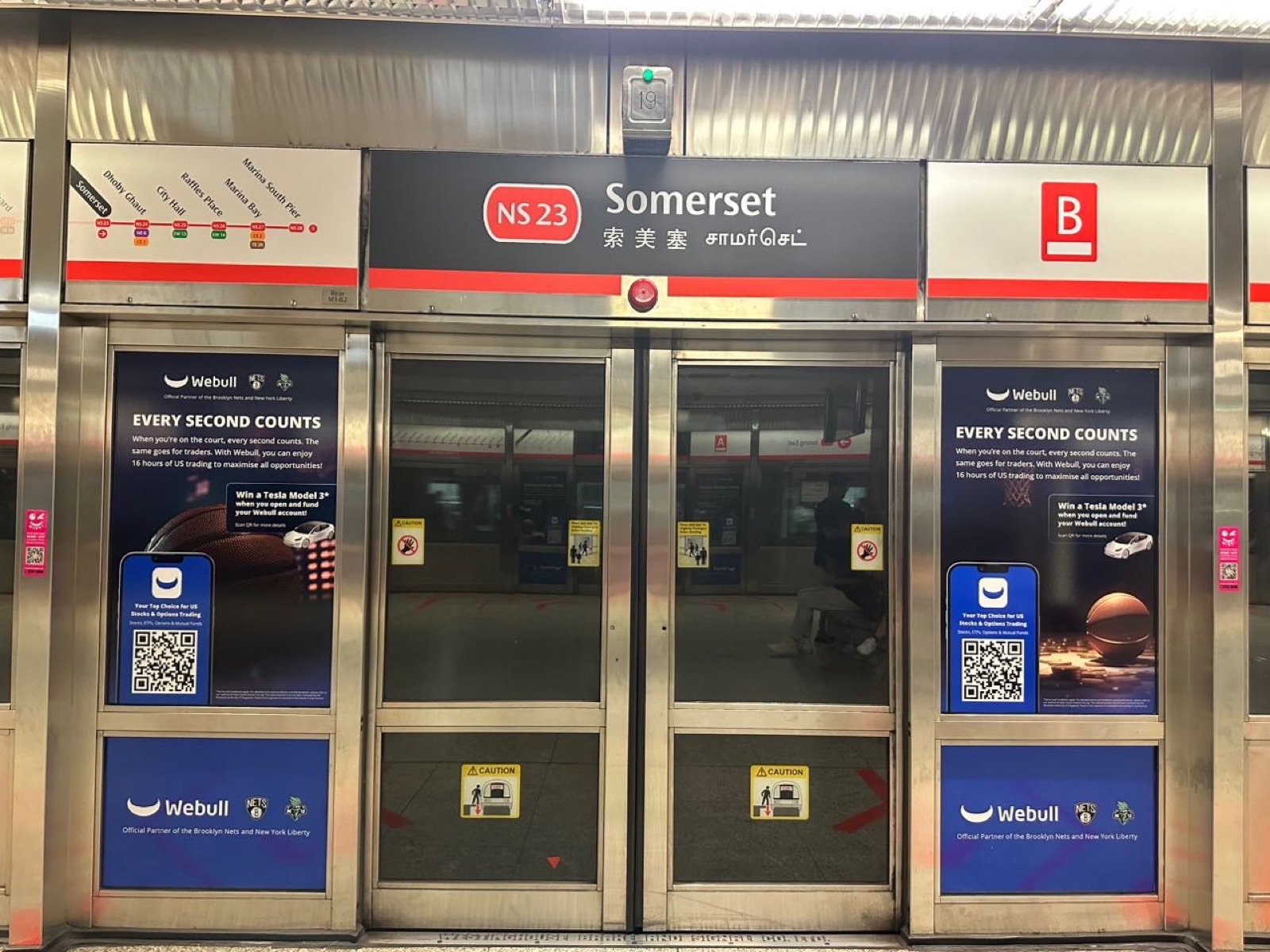 Webull campaign creative on the platform screen doors at Somerset MRT station