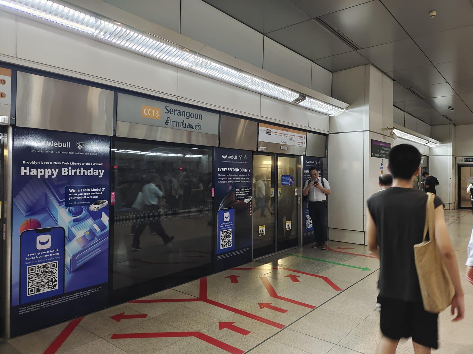 Webull platform screen doors at Serangoon MRT with commuters